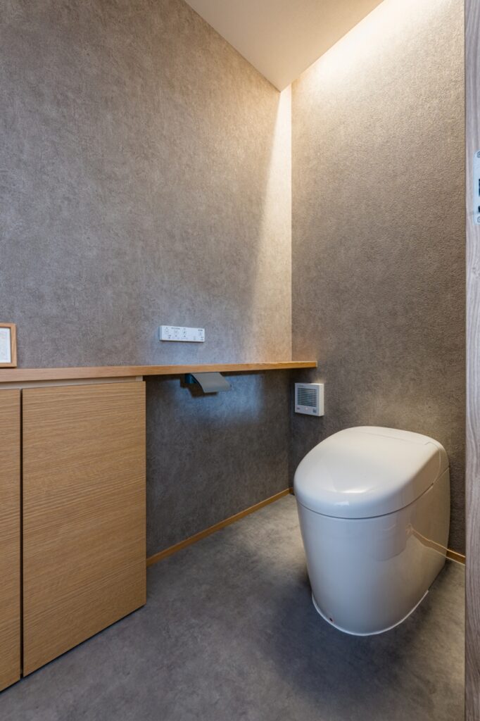 グレーの壁紙と間接照明で落ち着きのあるトイレ空間